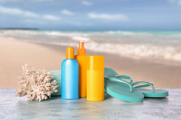 Sunscreen creams, flip-flops and coral on table at sea resort - Photo, Image