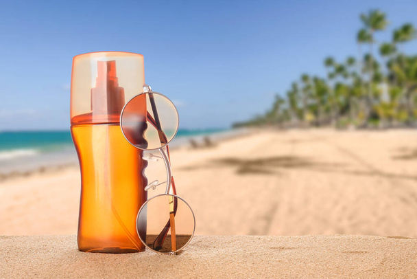 Sunscreen cream and sunglasses on sand at sea resort - Foto, Imagem