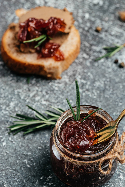 Red onion marmalade jam confiture in jar. Vegetable jam on dark background. Delicious sauce. French cuisine. Food recipe background. space for text. - Foto, afbeelding
