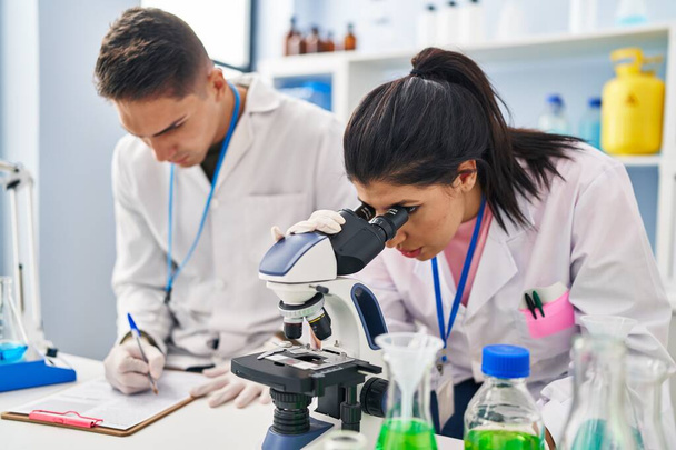 Partenaires scientifiques hommes et femmes travaillant au microscope en laboratoire - Photo, image