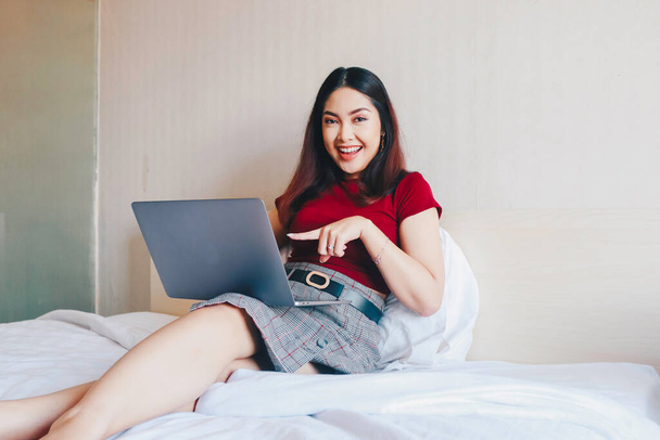 Young Asian businesswoman smiling while working on laptop computer at home. Portrait of positive business woman looking at laptop screen indoors - Foto, Imagem