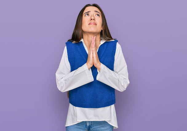 Jong Latijns-Amerikaans meisje draagt casual kleding bedelen en bidden met de handen samen met hoop uitdrukking op het gezicht zeer emotioneel en bezorgd. bedelen.  - Foto, afbeelding