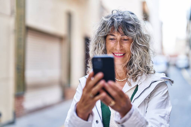 Middle age woman smiling confident using smartphone at street - Fotoğraf, Görsel