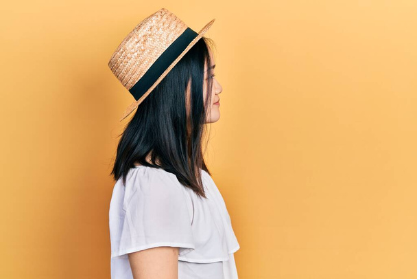 Young chinese girl wearing summer hat looking to side, relax profile pose with natural face with confident smile.  - Foto, Imagen