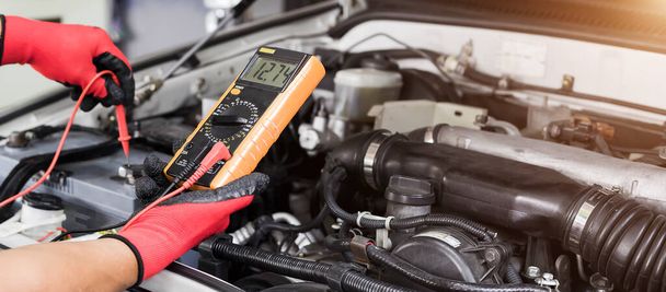 Ein Techniker überprüft die Autobatterie auf Verfügbarkeit. - Foto, Bild