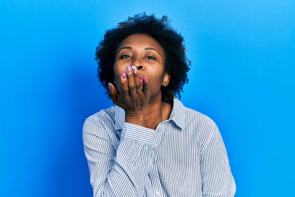 Giovane donna afroamericana indossa abiti casual guardando la fotocamera soffiando un bacio con la mano in aria di essere bella e sexy. espressione d'amore.  - Foto, immagini