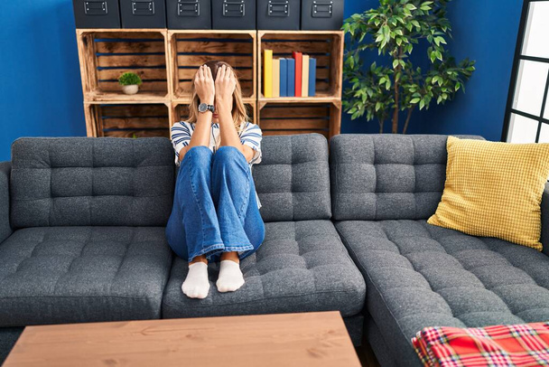 Joven mujer rubia deprimida sentada en el sofá en casa - Foto, imagen