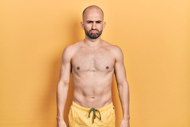 Young bald man wearing swimwear depressed and worry for distress, crying angry and afraid. sad expression.  - Фото, изображение