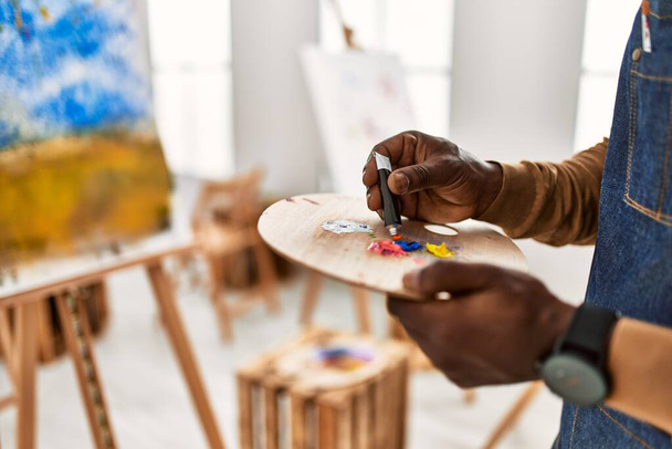 Αφρο-Αμερικανός καλλιτέχνης άνθρωπος ανάμειξη χρώμα στο στούντιο τέχνης παλέτα. - Φωτογραφία, εικόνα