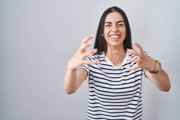 Junge brünette Frau in gestreiftem T-Shirt schreit frustriert vor Wut, Hände versuchen zu würgen, schreit verrückt  - Foto, Bild
