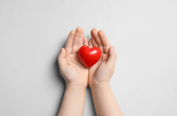 Child holding red heart on light grey background, top view - Foto, immagini