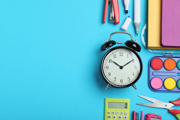 Flat lay composition with alarm clock and different stationery on light blue background, space for text. School time - Φωτογραφία, εικόνα