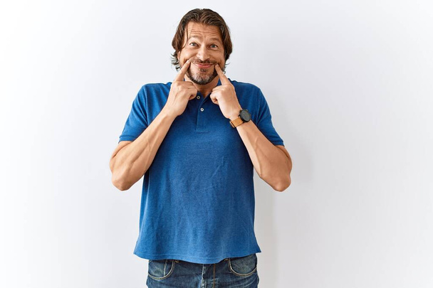 Handsome middle age man standing together over isolated background smiling with open mouth, fingers pointing and forcing cheerful smile  - Foto, afbeelding