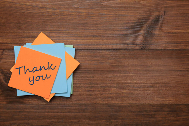 Orange sticker with phrase Thank You on wooden table, top view. Space for text - Foto, Imagem