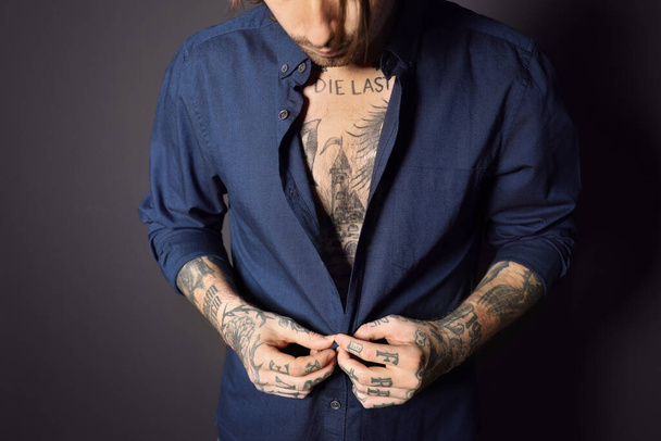 Young man with tattoos on body against black background, closeup - Fotoğraf, Görsel