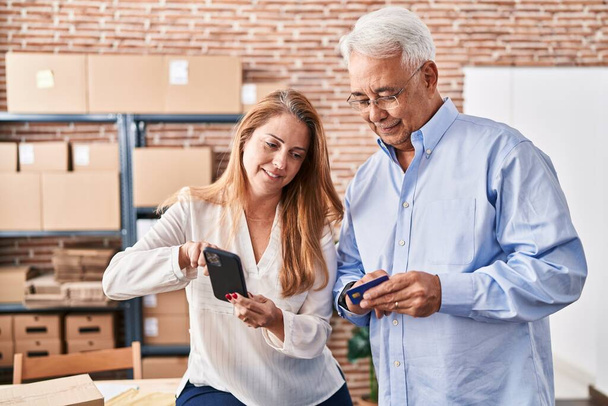 Мужчина и женщина среднего возраста электронной коммерции бизнес-работников с помощью смартфона и кредитной карты в офисе - Фото, изображение