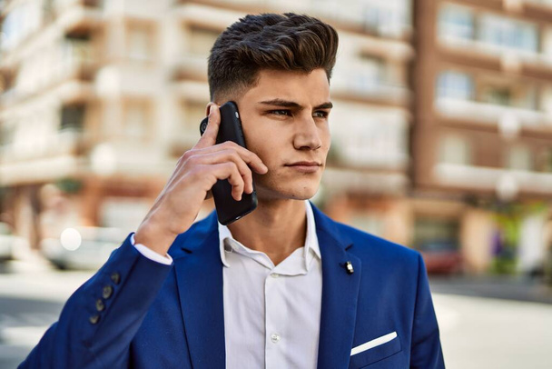 Young man talking on the smartphone wearing suit at street - Zdjęcie, obraz
