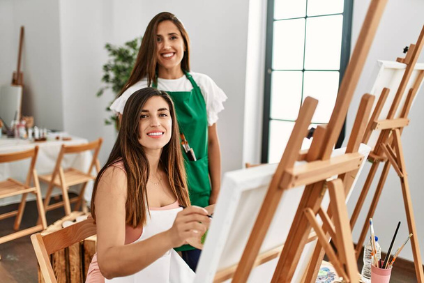 Student and teacher smiling happy painting at art school. - Photo, image