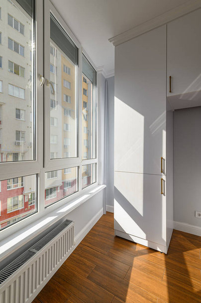 Cobertura aquecida vazia ou sala de estar com piso laminado de madeira e janelas de altura total e construído no armário - Foto, Imagem