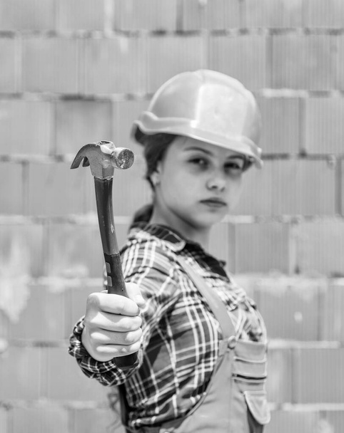 adolescente chica constructor en protector casco uso martillo, herramienta de construcción. - Foto, imagen