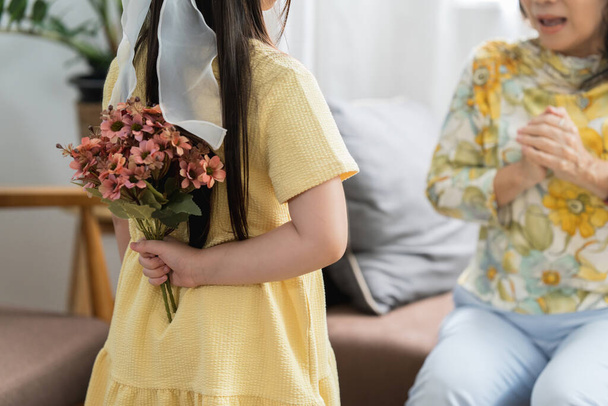 Happy moment of Little daughter surprise her loving mother on holiday by giving flowers. - Photo, Image