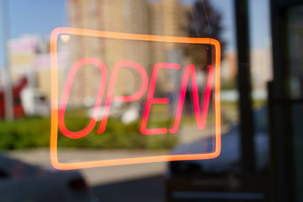 Neon sign open on the glass door of a shop or cafe. Selected focus. High quality photo - Foto, afbeelding