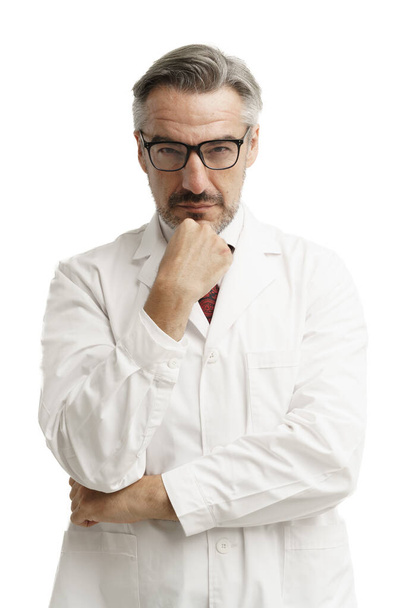 Attractive Caucasian senior man wearing gown suit looking toward to camera over isolated white background. Vertical image of senior man with thinking expression. - Photo, Image