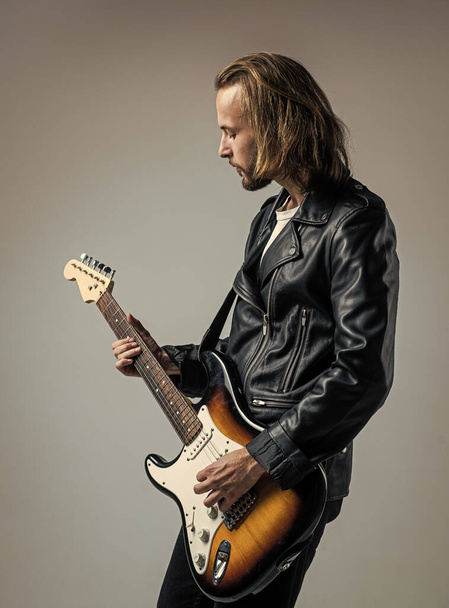 hard rock. rock music style. musician guitar player. masterfully playing music. stylish crazy man. string musical instrument. bearded rocker in leather jacket. man long hair play electric guitar. - Foto, Bild