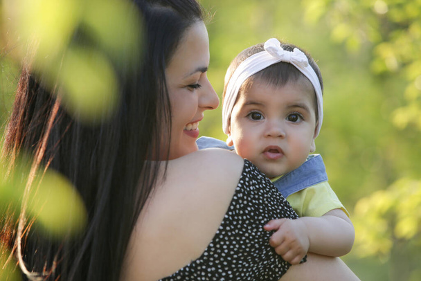  Молодая мама наслаждается идиллическим летним днем на свежем воздухе со своей маленькой девочкой. Семейный портрет в парке. - Фото, изображение