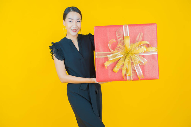 Portrét krásná mladá asijská žena úsměv s červeným dárkem box na barevném pozadí - Fotografie, Obrázek