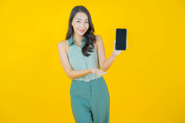 Retrato bonito jovem asiático mulher sorriso com telefone celular inteligente na cor de fundo - Foto, Imagem