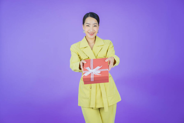 Portrait beautiful young asian woman smile with red gift box on color background - Foto, immagini
