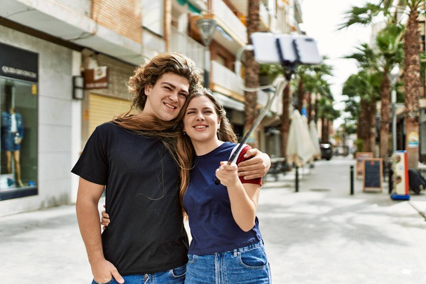 Joven pareja caucásica sonriendo feliz de pie en la ciudad. - Foto, imagen