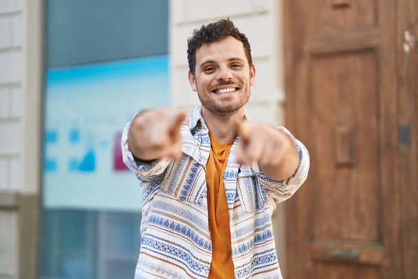 Genç İspanyol adam gülümsüyor. Kendine güveni tam, parmağıyla sokağı işaret ediyor. - Fotoğraf, Görsel