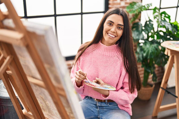 Junge hispanische Frau lächelt selbstbewusst Zeichnung im Kunstatelier - Foto, Bild