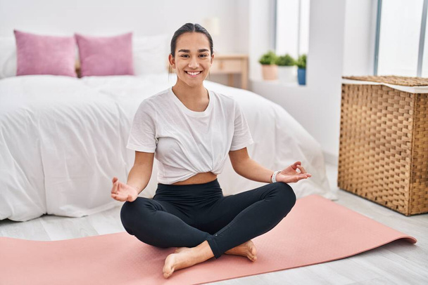 Genç İspanyol kadın yatak odasında kendine güvenen yoga eğitimi alırken gülümsüyor. - Fotoğraf, Görsel