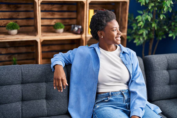 Αφροαμερικανή γυναίκα χαμογελά αυτοπεποίθηση κάθεται στον καναπέ στο σπίτι - Φωτογραφία, εικόνα