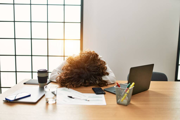 Donna ispanica di mezza età ha lavorato troppo con la testa sul tavolo in ufficio - Foto, immagini