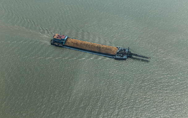 Грузовой корабль на реке, перевозящий песок в солнечный летний день
 - Фото, изображение