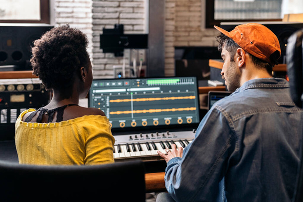 Stock photo of black woman working with male producer in music studio. - Zdjęcie, obraz