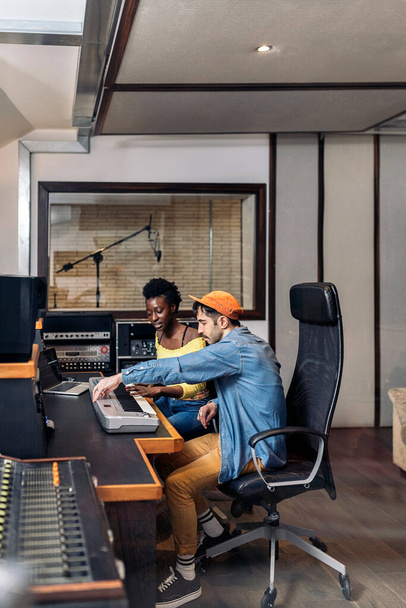 Stock photo of black woman working with male producer in music studio. - Foto, afbeelding