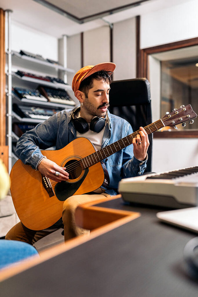 Stock photo of concentrated artist in music studio playing the guitar. - Photo, image