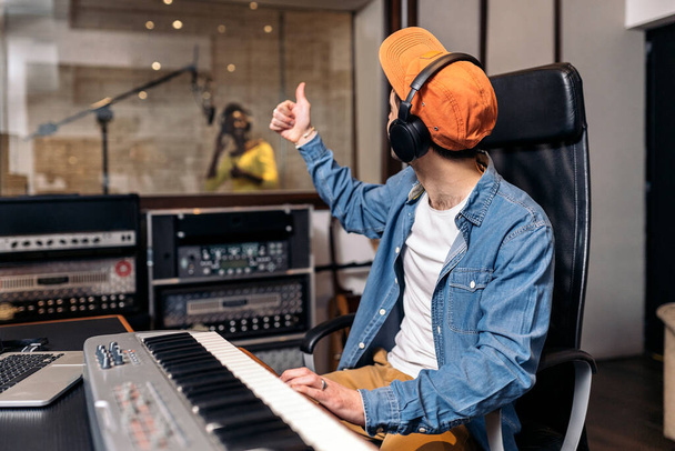 Фото продюсера мужской музыки, работающего с черной певицей в крутой музыкальной студии. - Фото, изображение