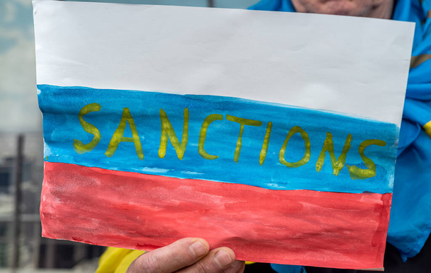 плакат в руках мужчин с санкционированием для России. цілковита ізоляція для терористичної держави. - Фото, зображення