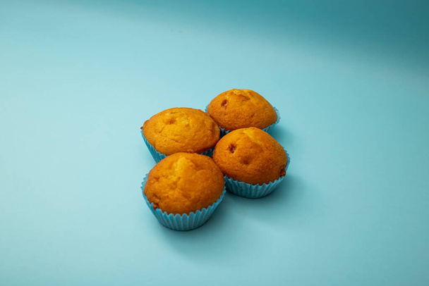 Φωτεινά cupcakes σε μπλε συσκευασία σε μπλε φόντο - Φωτογραφία, εικόνα