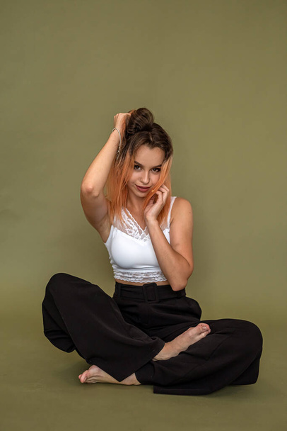 young european woman in stylish white top and black pants posing in full growth isolated on green background. fashion style concept - Foto, imagen