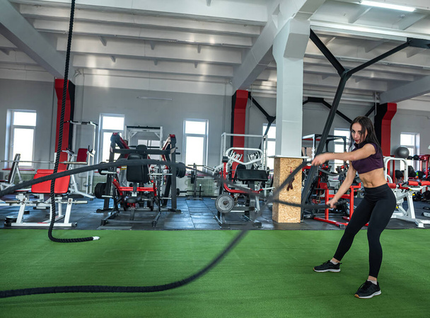 Young female trainer exercise training with rope in gym. Sports ground.  - Photo, Image