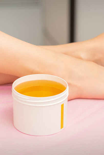Ženské nohy s bílou sklenicí vosku cukroví před odstraněním srsti v lázních - Fotografie, Obrázek