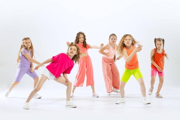Contemporary dances. Happy, sportive little girls, kids in bright colorful clothes dancing modern dance isolated on white studio background. Concept of music, fashion, art, childhood, hobby. - Foto, immagini