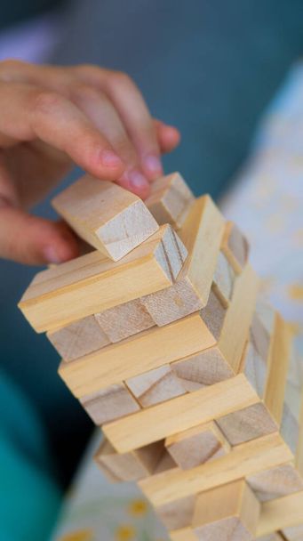 Jenga game playing. Kid hand putting wooden bricks. Closeup. Family fun and entertainment concept. High quality photo - Foto, Imagen